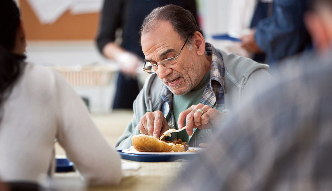 mature man eats in a soup kitchen
