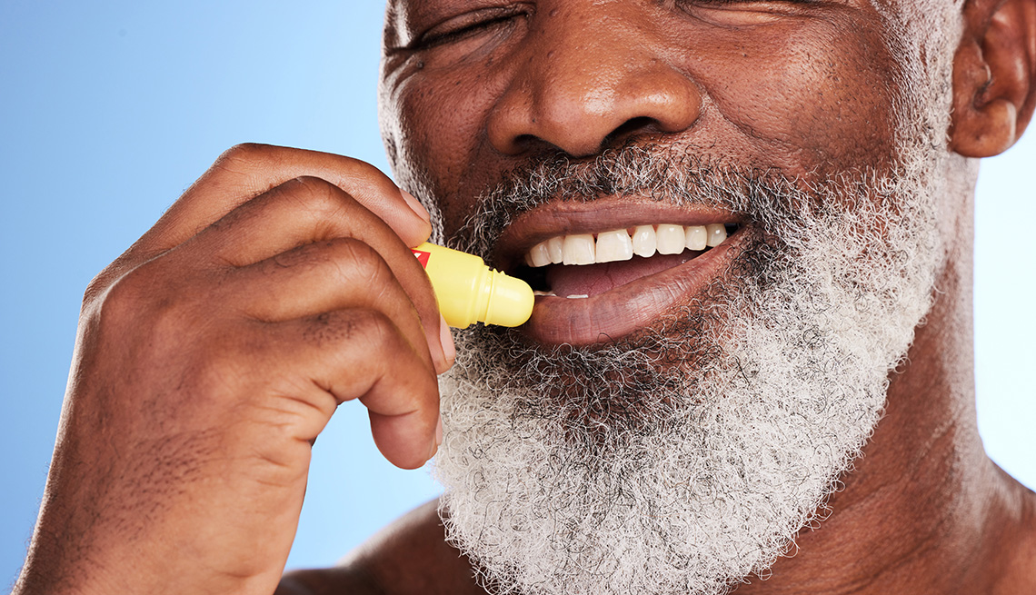 A man applying lip balm to his lips