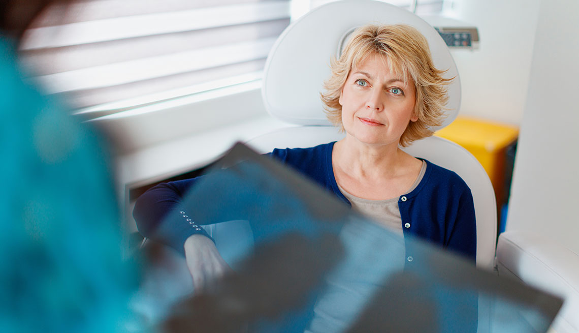 Female patient sitting in doctor's office as physician holds x-ray
