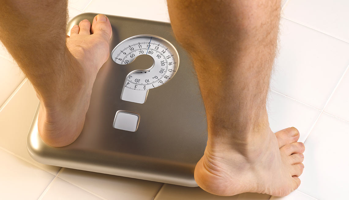 Man's feet stepping on scale that has a question mark on it