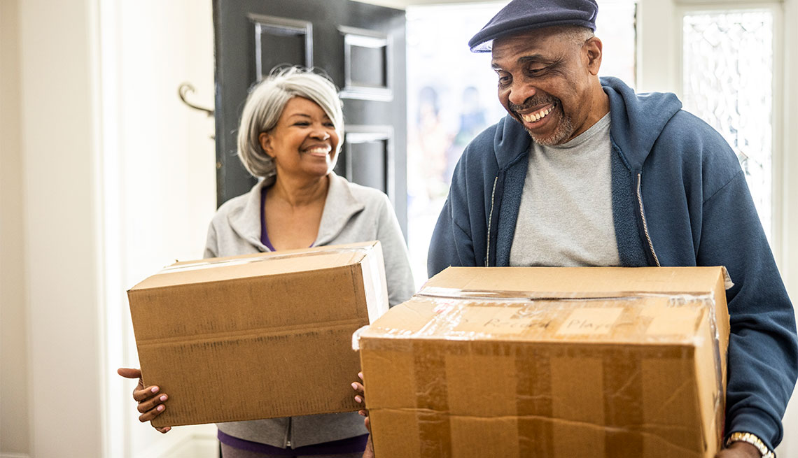 a couple carrying moving boxes