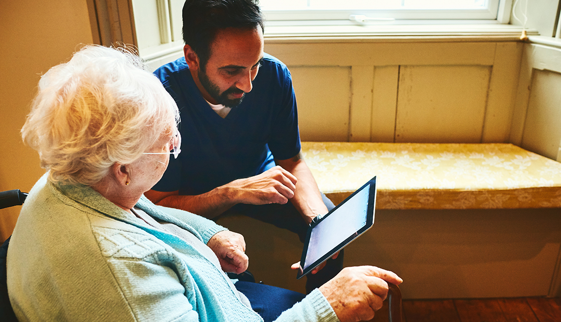 Healthcare worker with woman using digital tablet at care home