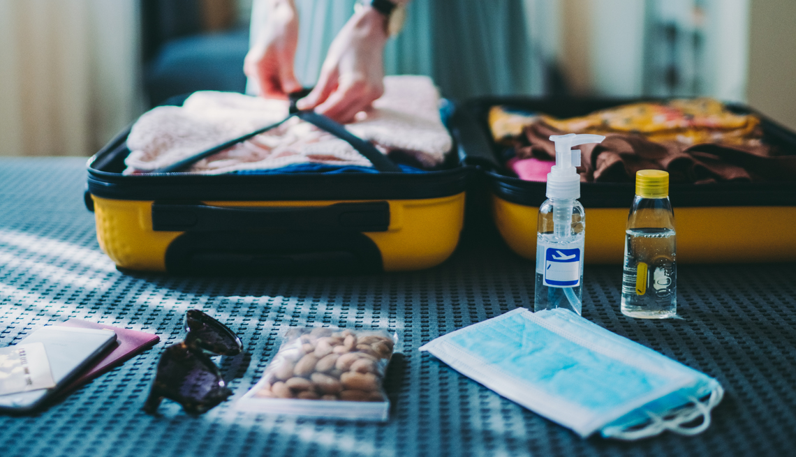 woman packing face masks and sanitizer to travel safely