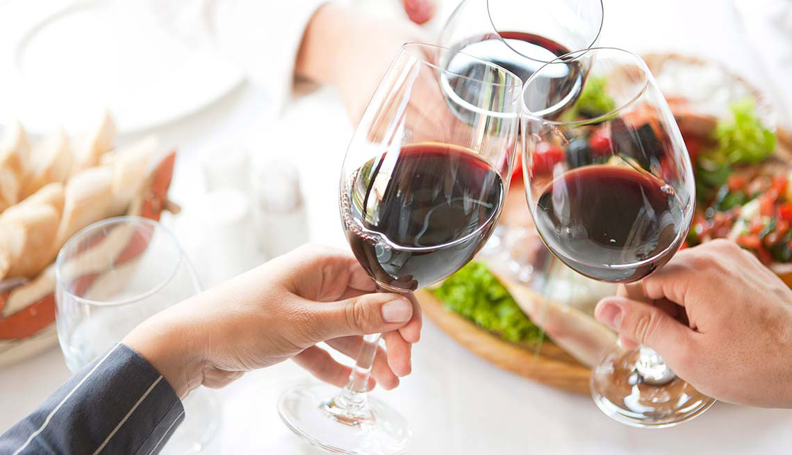 Dos personas brindan mientras toman vino