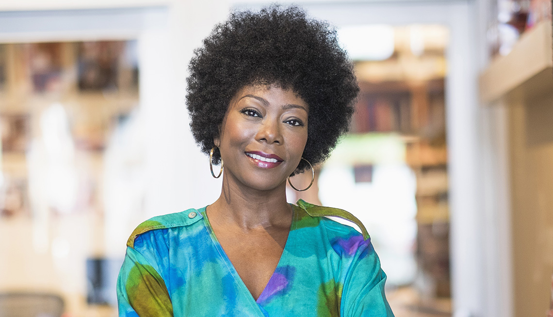 Una mujer con cabello rizado natural sonriendo.