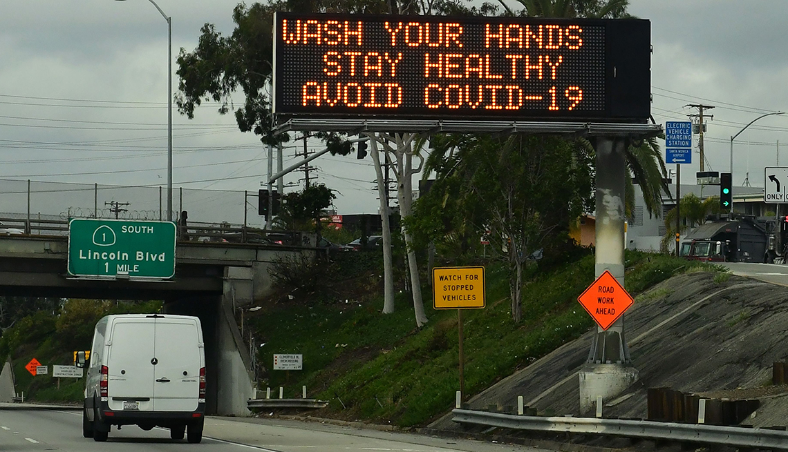 Vista de una autopista y un letrero electrónico que dice que laves tus manos y evites la COVID-19