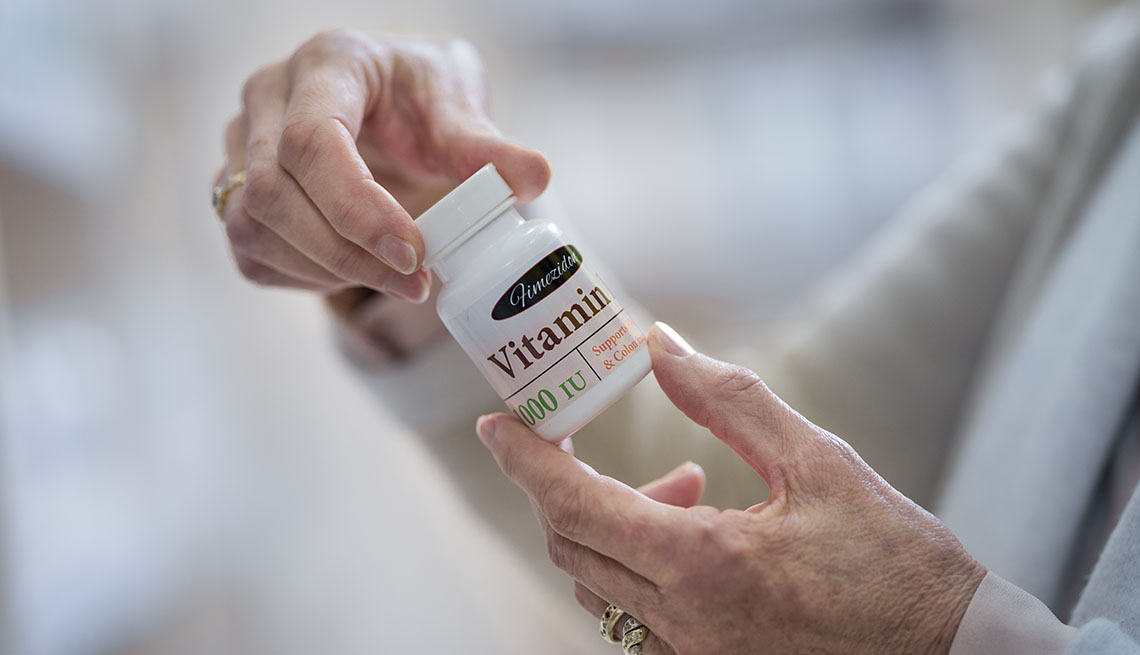 Una mujer examina un frasco de vitaminas