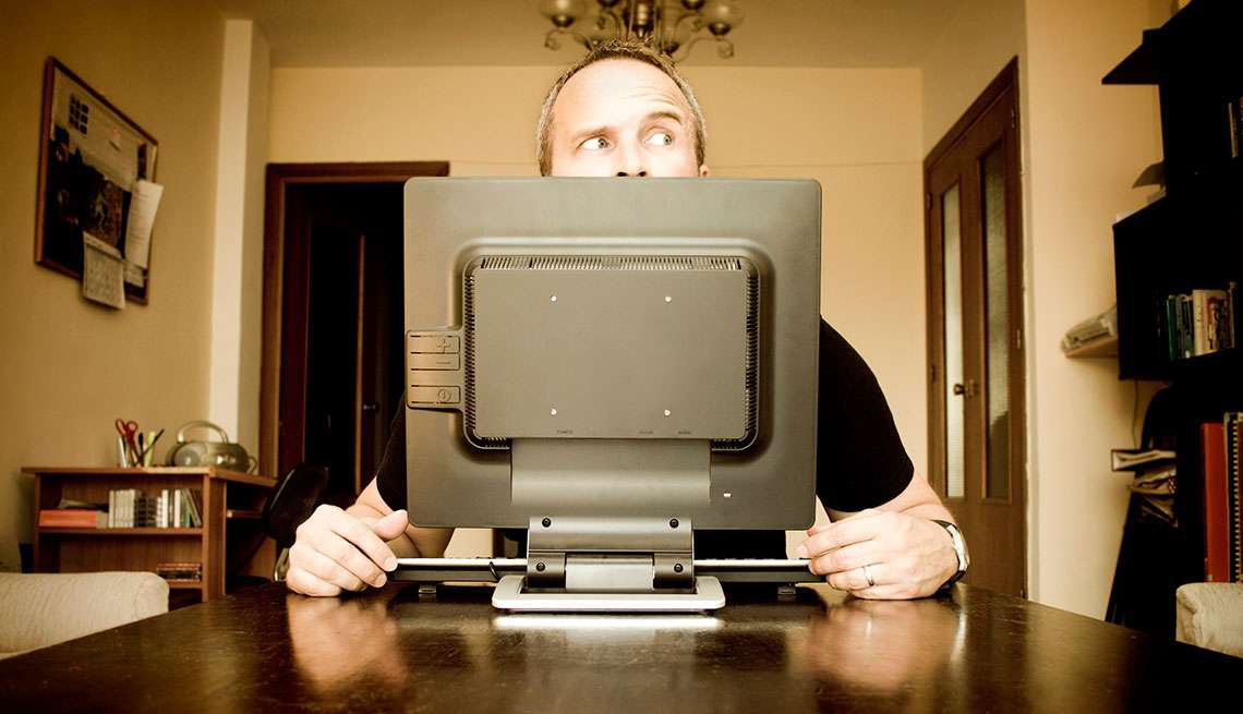 Hombre detrás de un monitor de una computadora mirando hacia un lado, como buscar trabajo a través de las redes sociales